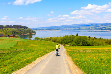 Woman cycling around Czorsztynskie lake near Niedzica village on sunny spring day, Pieniny Mountains, Poland