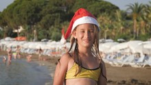 Little Adorable Girl In Red Santa Hat Having Fun At Beach.