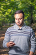 © beerlogoff - Portrait of handsome adult man sending a text message while standing in the city park