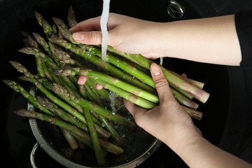 Woman washing fresh raw asparagus over sink, closeup