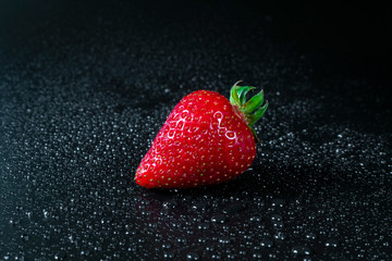 Fresh and juicy  red strawberriy on black background  with drops of water