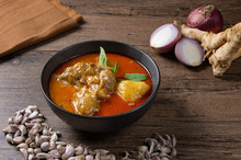 Chicken Massaman Curry In Black Bowl With Herb And Spices On Wooden Background. Thai Authentic Food Called Massaman Kai.