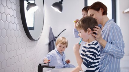 Wall Mural - Mother with small children in pajamas in bathroom at home, brushing teeth.