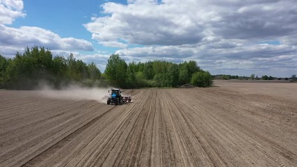 Wall Mural - Blue tractor working on spring field, aerial view. Agriculture - aerial view of harvest fields with tractor. Farmer seeding crops at field. 
