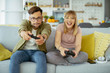 © JustLife - Husband and wife playing video game with joysticks in living room.Loving couple are playing video games at home.