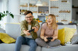 © JustLife - Husband and wife playing video game with joysticks in living room.Loving couple are playing video games at home.