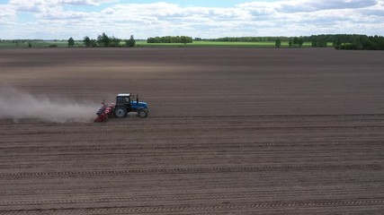 Wall Mural - Blue tractor working on spring field, aerial view. Agriculture - aerial view of harvest fields with tractor. Farmer seeding crops at field. 
