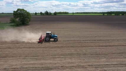 Wall Mural - Blue tractor working on spring field, aerial view. Agriculture - aerial view of harvest fields with tractor. Farmer seeding crops at field. 
