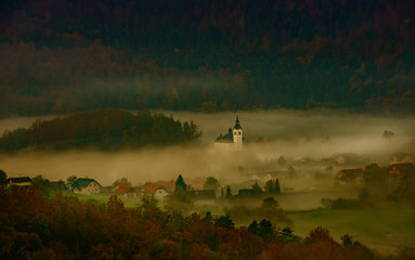 Wall Mural - sunrise on the hill where the church is between the trees and the fog completes the panorama