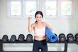 © Southtownboy Studio - Pretty young asian sportswoman holding fitness mat while standing in gym.