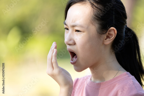 Asian child girl checking breath with her hand,woman have bad breath,bad smell,feel stinks,foul mouth from inside the mouth,tongue and tooth decay,oral health problems,halitosis,health care concept