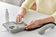 © Syda Productions - hygiene and disinfection concept - close up of woman hands cleaning desk phone with hand sanitizer and paper tissue