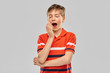 © Syda Productions - childhood, fashion and people concept - portrait of tired yawning boy in red polo t-shirt over grey background