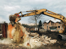 House Crushing And Collapse. Excavator Destroying Brick House On Land In Countryside. Bulldozer Clearing Land From Old Bricks And Concrete From Walls With Dirt And Trash. Ruining House