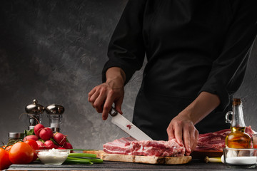 Wall Mural - Slicing fresh pork ribs for frying on a background of vegetables. Cooking