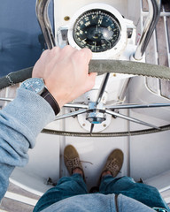 Mano de hombre manejando el timón de un barco de vela visto desde arriba