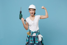 Laughing Young Woman In Protective Helmet Hardhat Hold Electric Drill Isolated On Blue Background. Instruments Accessories For Renovation Apartment Room. Repair Home Concept. Showing Biceps, Muscles.