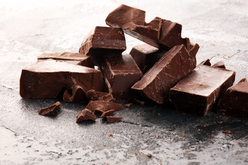 Wall Mural - close up of bitter chocolate bars and broken piesces on rustic background.