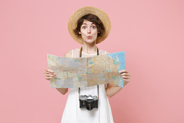 Amazed young tourist woman in summer white dress hat with photo camera isolated on pink background studio. Female traveling abroad to travel weekend getaway. Air flight journey concept. Hold city map.