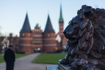 Holstentor in Lübeck with lion statue in the foreground UNESCO World Heritage Site landmark Gothic style historic cityscape ornaments restored brick Petrikirche big cat