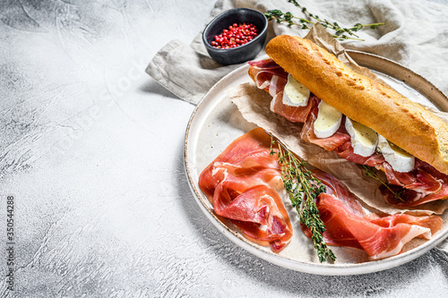 Cuadros en Lienzo baguette sandwich with jamon ham serrano, paleta iberica, Camembert cheese on the cutting Board