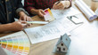 © PIC SNIPE - Interior designer and Architect choosing color in color swatch samples chart for house coloring selection in office with blueprint. Construction concept.