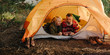 © Criene Images - Caucasian elderly couple browsing on phone while laying in bedroll in tent