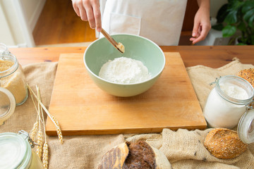 Cook adding butter to wheat flour in ceramic bowl. Dough preparation for delicious pastry and bread. Studio shot. Side view. Homemade bakery and cooking at home concept