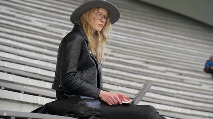 Young beautiful woman tries to find a new idea for her script, working with laptop, black color clothes