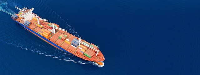 Aerial drone panoramic photo of industrial container tanker cruising in open ocean deep blue sea	
