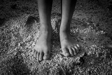 The Feet Of The Poor Asian Children Stood On The Sand Pile.