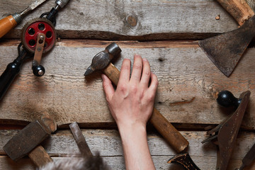 Hand holds old carpentry tools on wooden background.