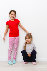 Wall Mural - Two cute little girls in full growth, in the studio on a white background. The concept of a happy childhood, Beauty and fashion. Isolated.