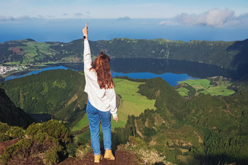 Young woman tourist standing with the view to the mountain lake