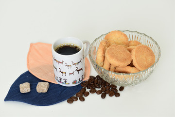 Cup of black coffee, two pieces of brown sugar and vase with cookies on white background