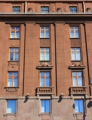 Historic building architecture with classic style simple windows in row. Multi-story old house facade, dark brown colored walls with windows. Residential city house facade, close up exterior detais