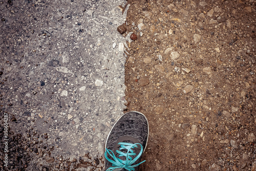 Fotografía Zapatilla sobre suelo mitad naranja terreno, mitad charco