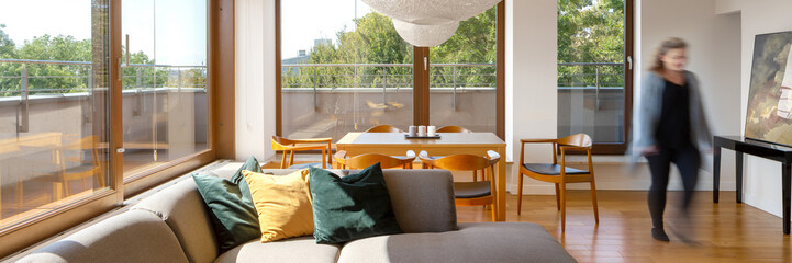 Woman in sunny living room, panorama