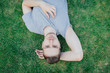 © alexander132 - A man in grey T-shirt lying on green grass, summer. Resting man