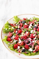 Sticker - Salad with berries-raspberry, blueberry, sweet cherry, red onion, feta cheese, pine nuts . Dressed with raspberry vinaigrette. Soft focus.