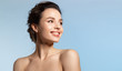 canvas print picture - Toothy smiling young woman with shiny glowing perfect facial skin and bare shoulder looking aside.