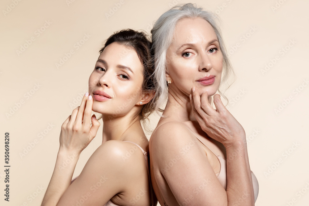 Elderly and young women with smooth skin and natural makeup standing back-to-back.  - obrazy, fototapety, plakaty 
