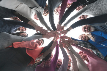 Creative business team stacking hands together in office