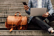 © kalinichenkod - businessman sits on a shoe with laptop and brown leather bag