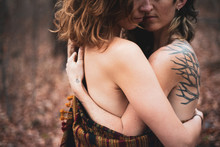 artistic faceless portrait of female gay couple hugging in woods