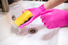 A Hand In A Pink Glove Washes A Washbasin In The Bathroom With A Sponge With Foaming Detergent. Cleaning Company Cleans The House. Disinfection Of The Senile Node From Viruses And Bacteria.