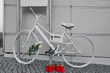 Berlin Germany, white ghost bike as a memorial to a biker who was killed in Berlin city traffic, closed near the city center, white roses with green leaves and red candles as a commemoration