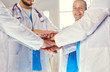 © lenets_tan - Doctors and nurses in a medical team stacking hands