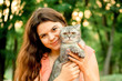 © SValeriia - Cheerful beautiful brunette girl in the park is sitting with a cat. happy photoshoot with a pet cat on the street..