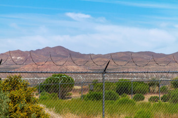 Chainlink fence with barded wire in a rural desert landscape